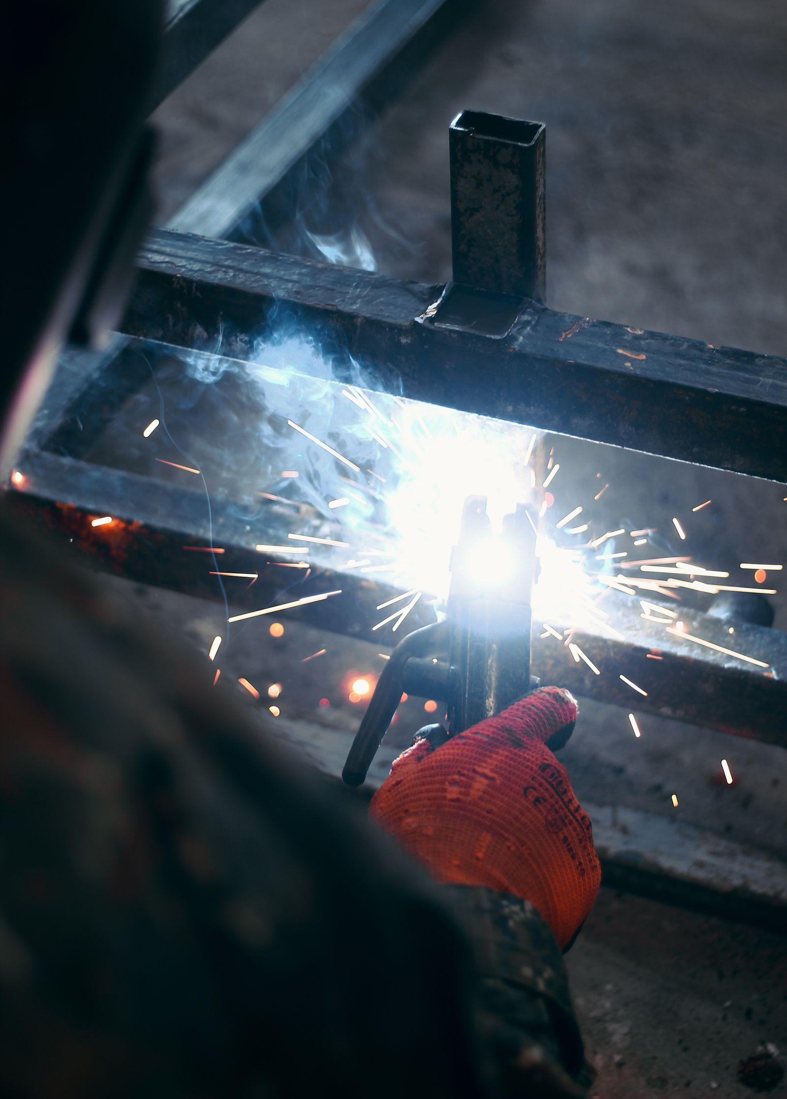 Saldatura di un telaio metallico in officina, con le scintille attorno alla torcia